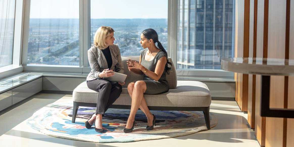 Two female executives discuss business in a corporate office.