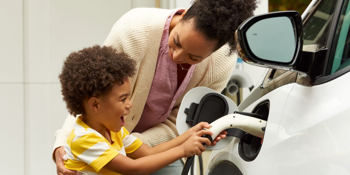 A mother and her son plug in an electric vehicle.